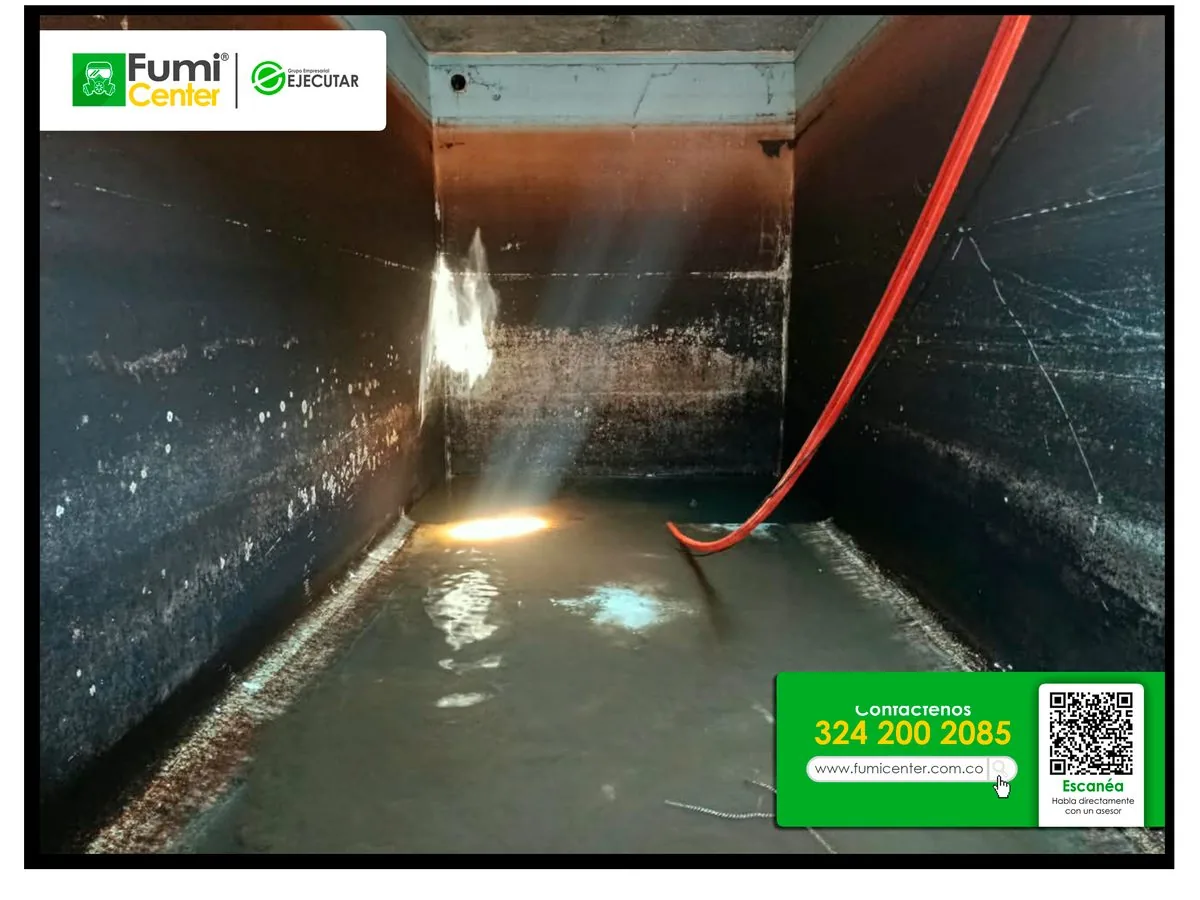 Cisterna subterránea de concreto con agua residual durante el vaciado, iluminada con linterna